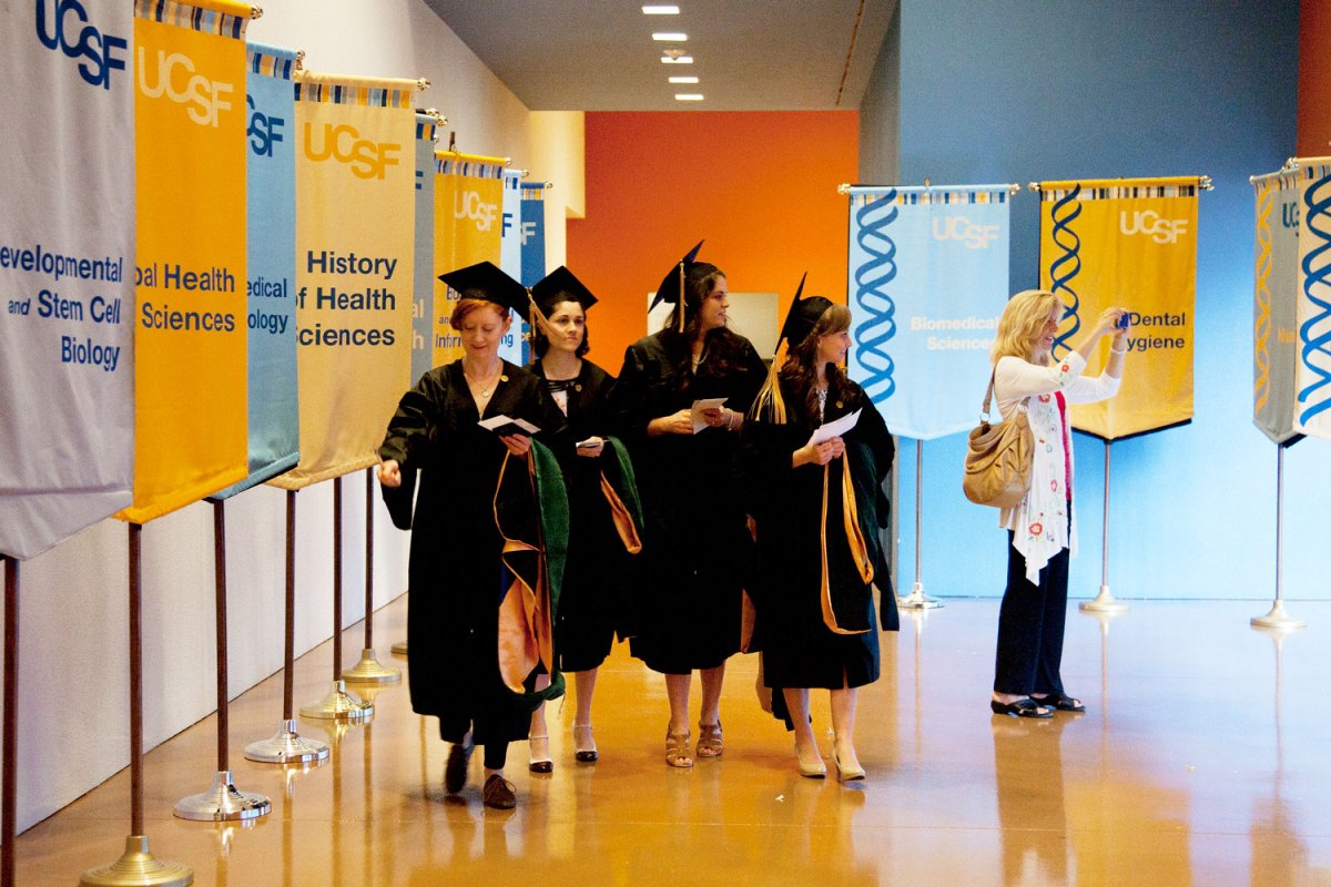 Graduate Division students walk through a hall of flags representing the many degree programs offered in the division.