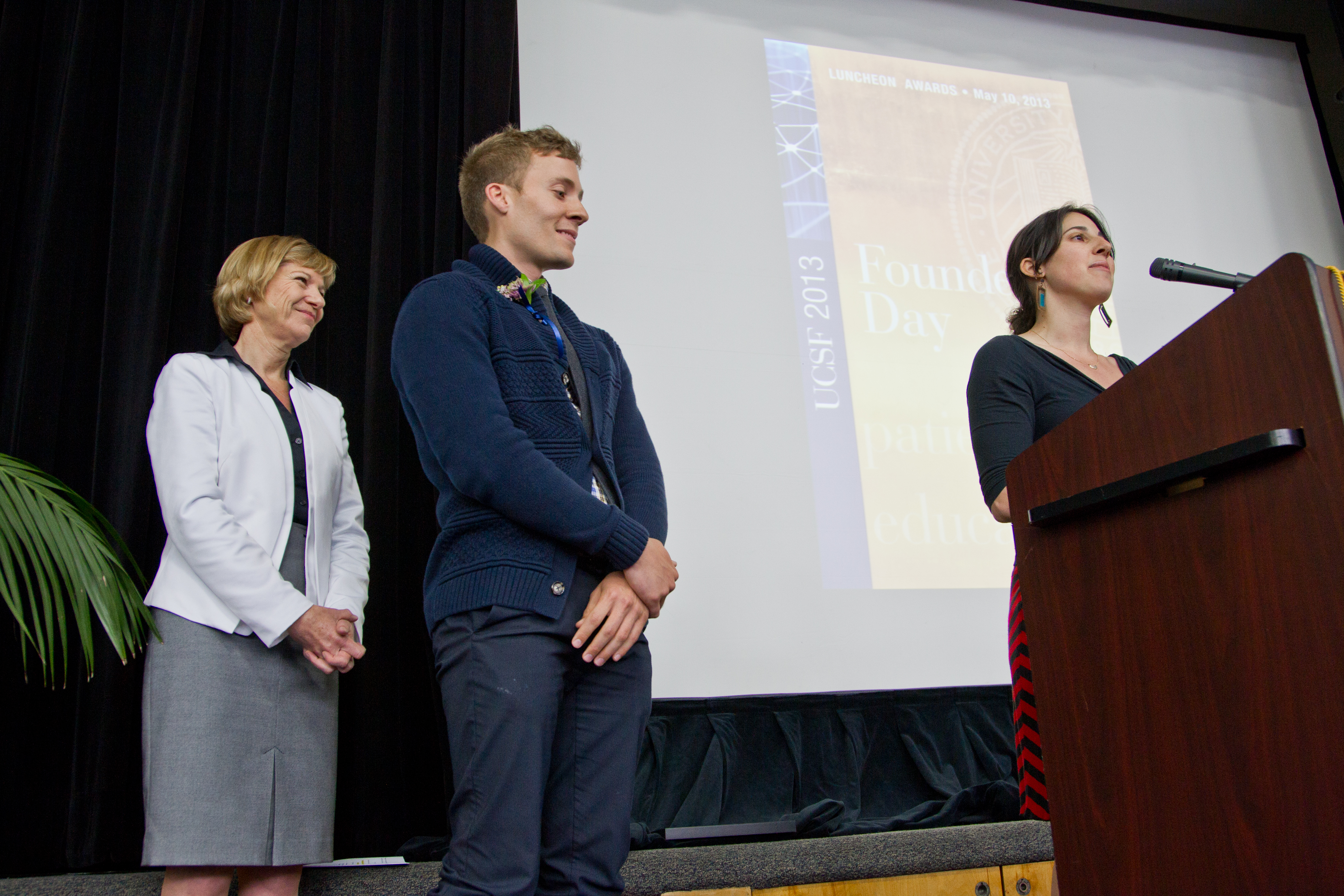 With Chancellor Susan Desmond-Hellmann looking on, ourth-year medical students Kate Hirschmann-Levy and Robert Pitts, winners of the public service award in the student category, talk about the work helping incarcerated women learn about basic health care.