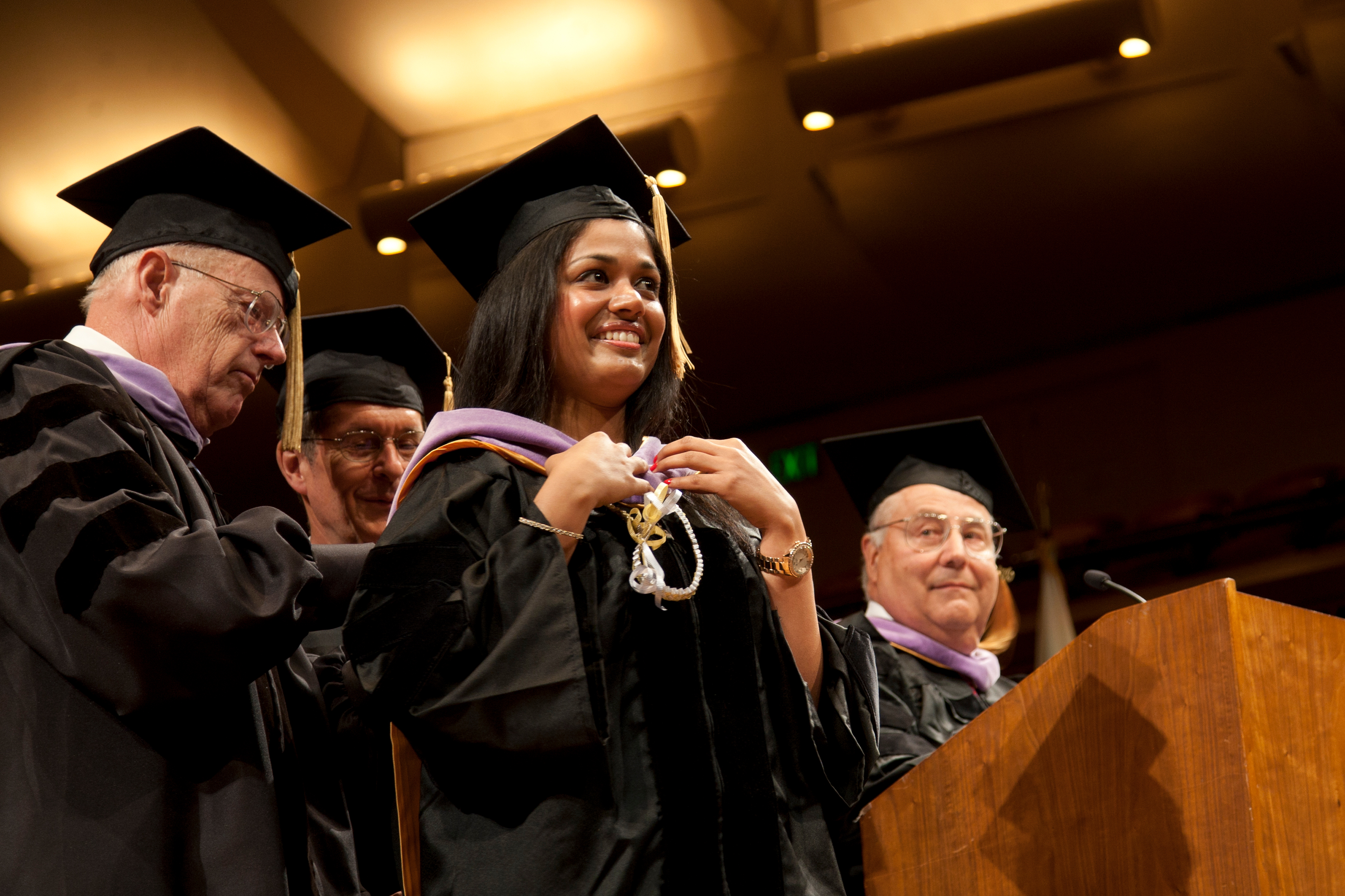 Graduate Prema Aggarwal is hooded during the commencement ceremony. The most important element of academic regalia is the hood, which is lilac, the color that denotes a doctor of dentristry.