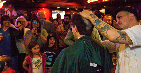 Crowd watches a H=head-shaving event to benefit childhood cancer research.