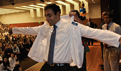 Jay S. Rajan receives help putting on his first white coat in an annual ceremony