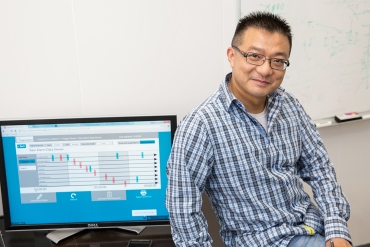 Xiao Hu, PhD, stands in front of his computer with information about patient-monitoring alarms