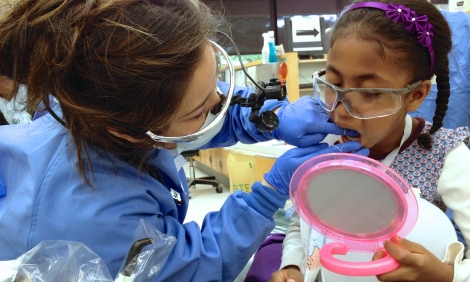 A UCSF School of Dentistry student teaches a young patient proper flossing techniques