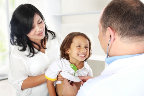 stock image of doctor performing checkup on a young boy being held by his mother