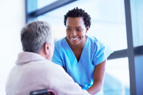 stock image of nurse smiling at an elderly male patient in a wheelchair