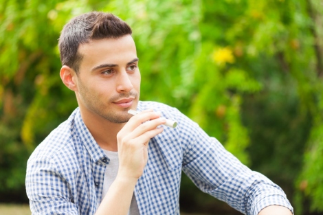 stock image of man holding an electronic cigarette in a park