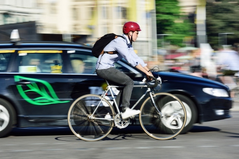 a man rides a bicycle near a car on a street