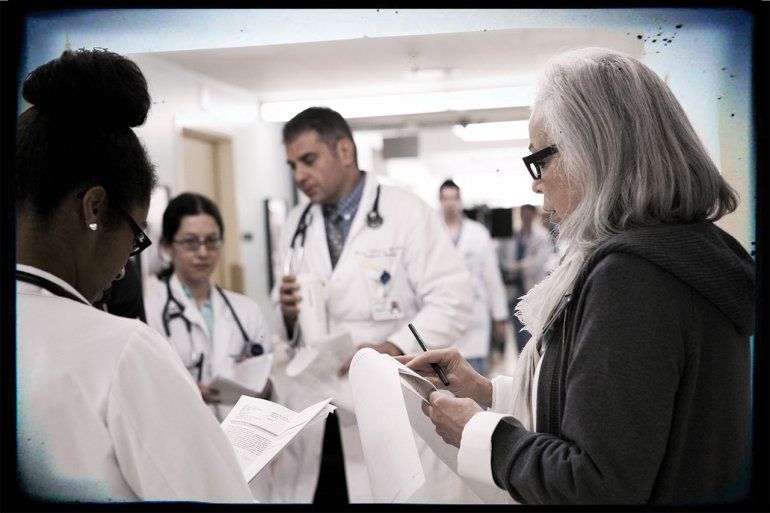 Nancy Ascher talks to medical students in the hallway of a hospital.