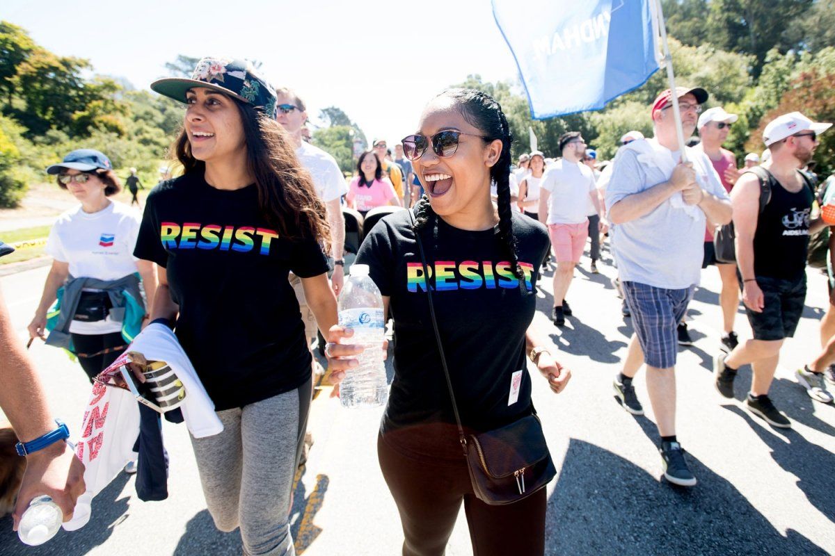 Ladan Khoddam walks alongside Kendall Parks both waring black t-shirts with word "Resist" printed in rainbow colors