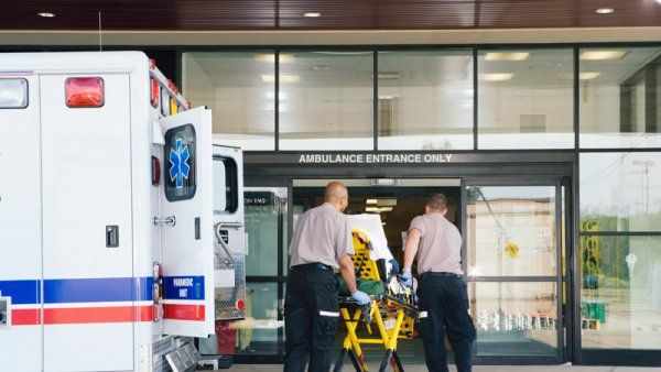 EMT taking stretchers through emergency room doors.