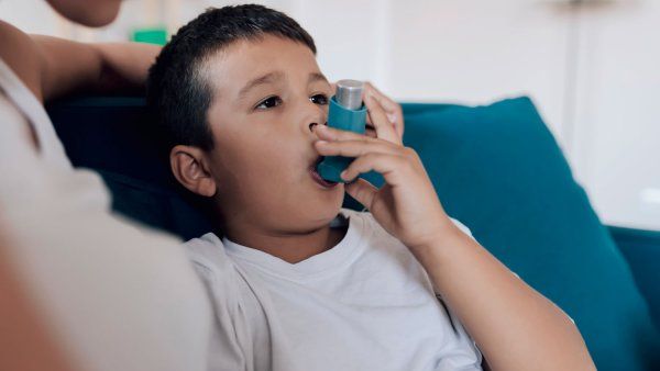 Child sitting on couch using an inhaler
