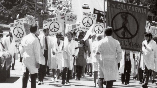 UCSF students in white coats hold peace signs at a Vietnam war protest.