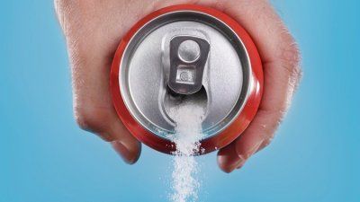 Hand pouring sugar from a soda can