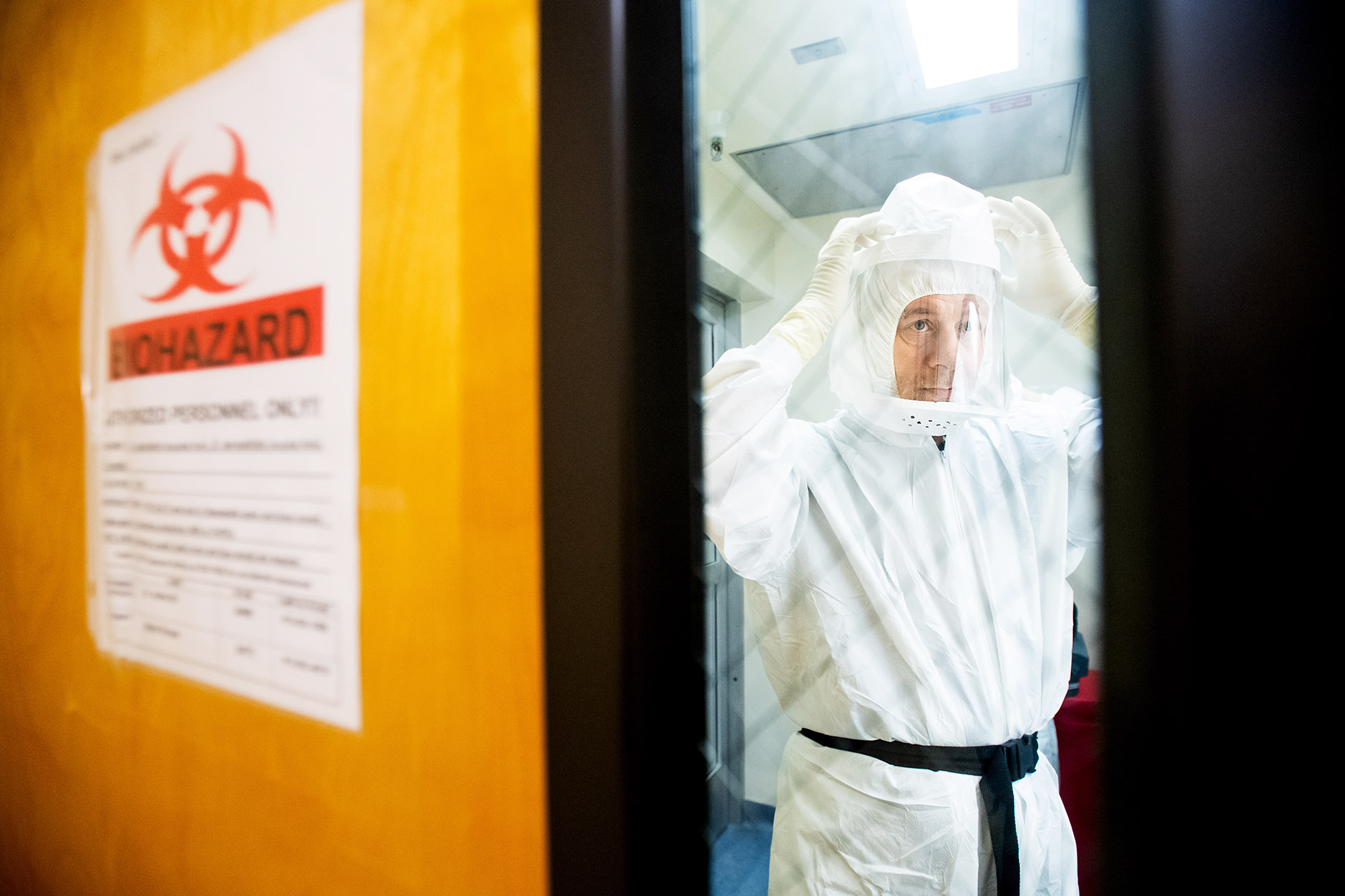 a man dresses in a biohazard suit in a lab