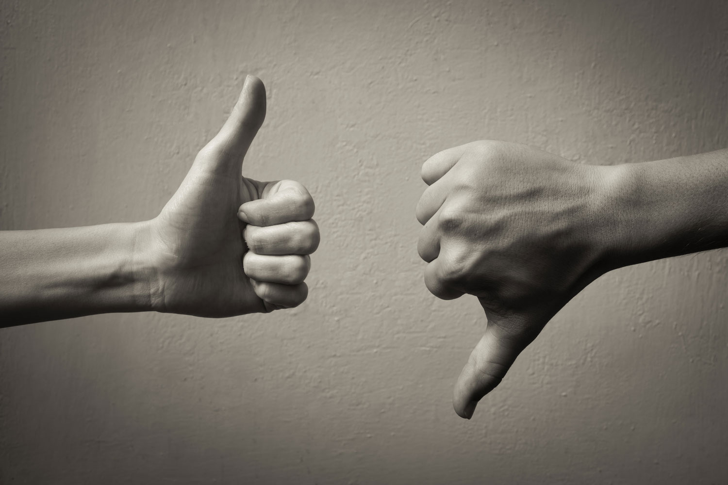 Black and white photo of one hand giving thumbs up, one hand giving thumbs down
