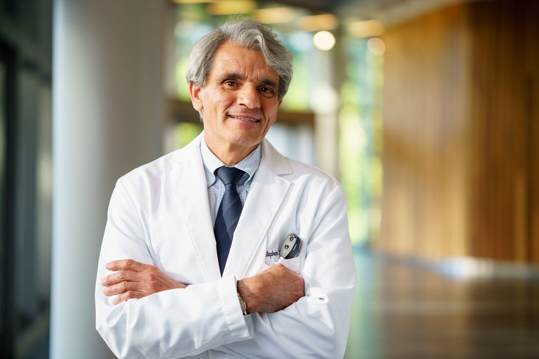 Stephen Hauser, MD, posing for a portrait in a white doctor's coat