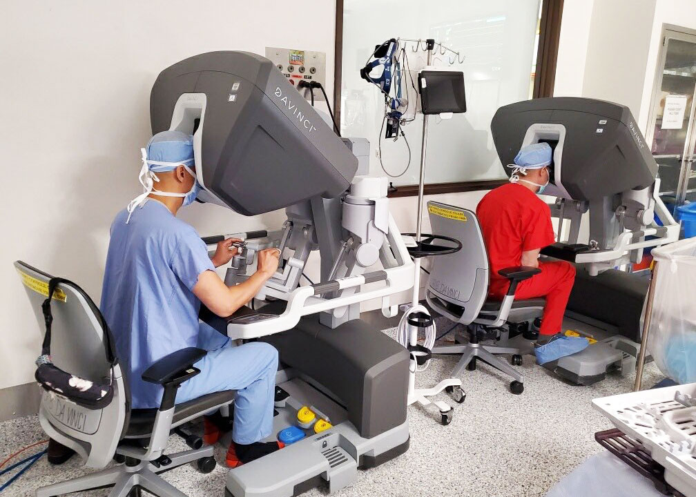 Doctors Tom C. Nguyen and Tobias Deuse in scrubs looking through 3D cameras as they perform robotic cardiac surgery 