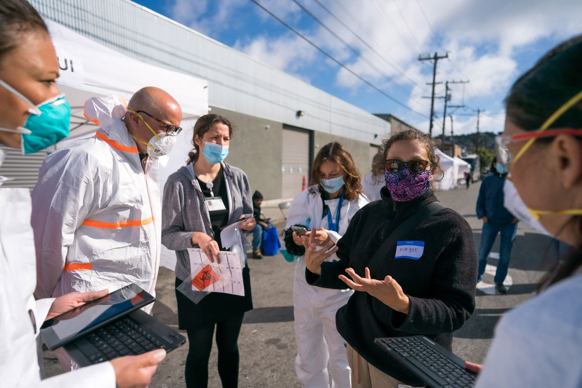 Margot Kushel gives directions to a group of masked health professionals in an outdoor setting
