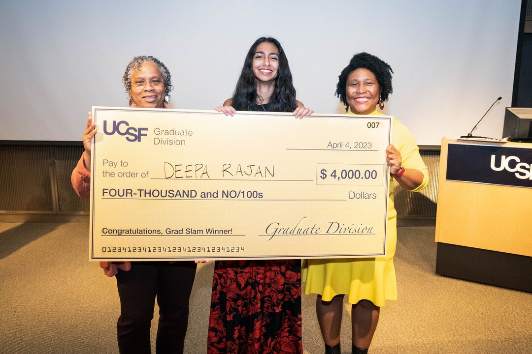 Deepa Rajan (center) holds a large check for $4,000 along with Niquet Blake (left) and D'Anne Duncan (right).