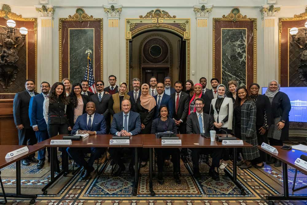 A large group photo at the 2023 Islamophobia Listening Session. United States Second Gentleman and other representatives sit at at able, and attendees stand behind them.