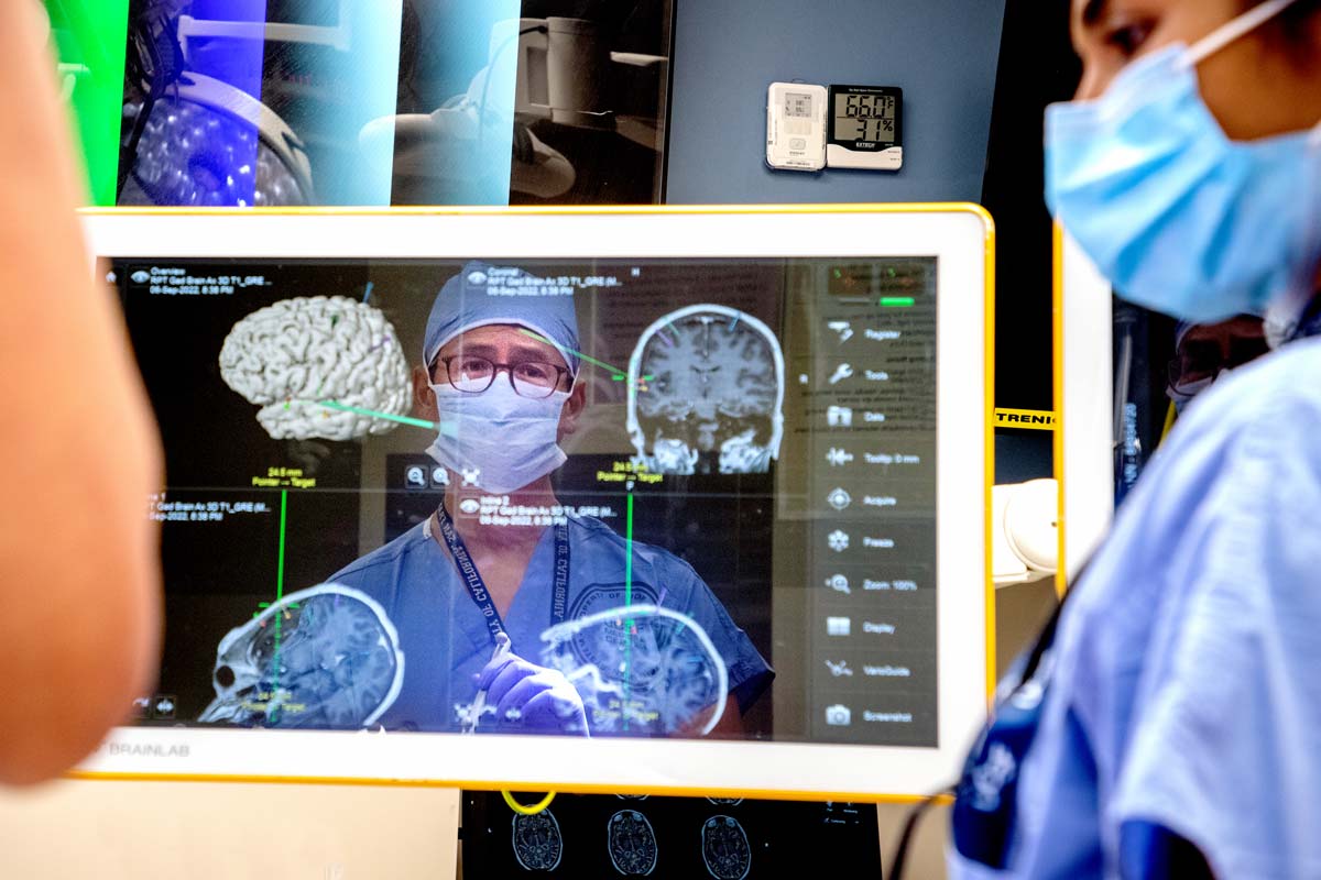 Neuroseurgon Eddie Chang looks at a screen with brain scrans during a brain surgery.