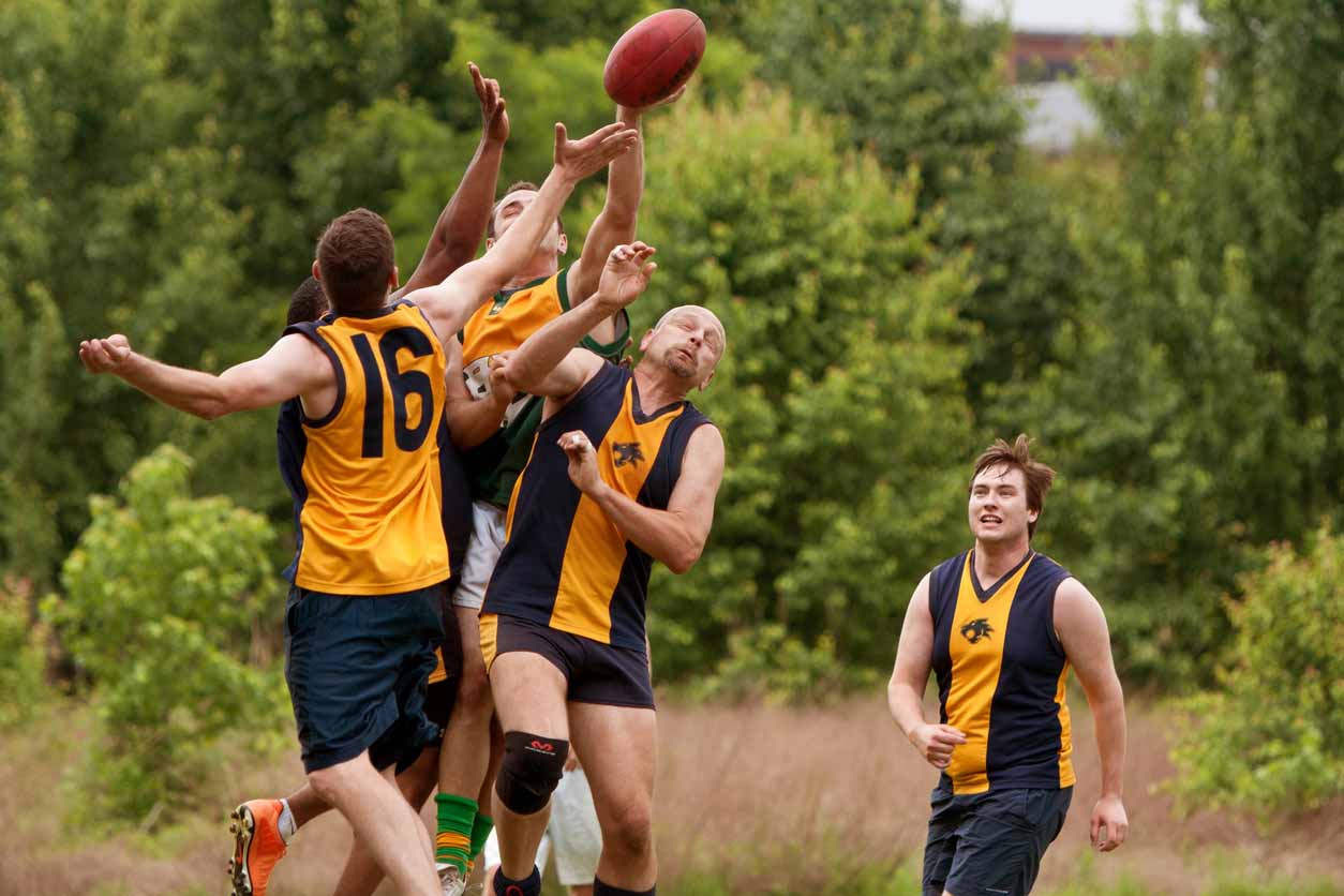 A group of male athelets playing Australian Rules Football.
