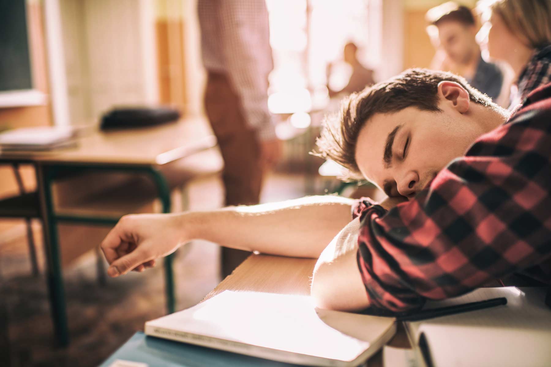 A teenager sleeps on his desk during class.