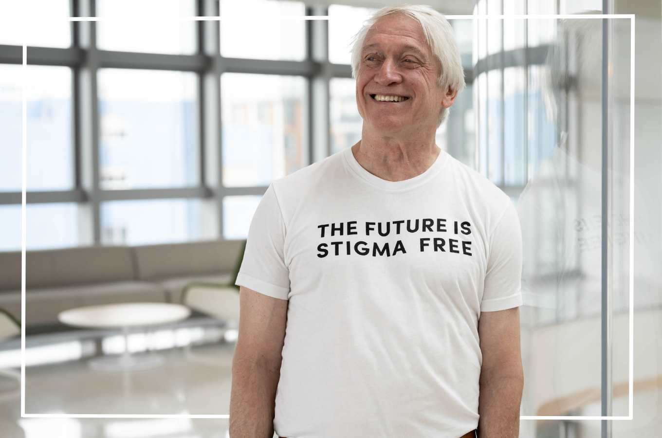 Man smiling wearing a white tshirt that reads "The Future is Stigma Free" courtesy of the UCSF Disability Awareness Campaign.