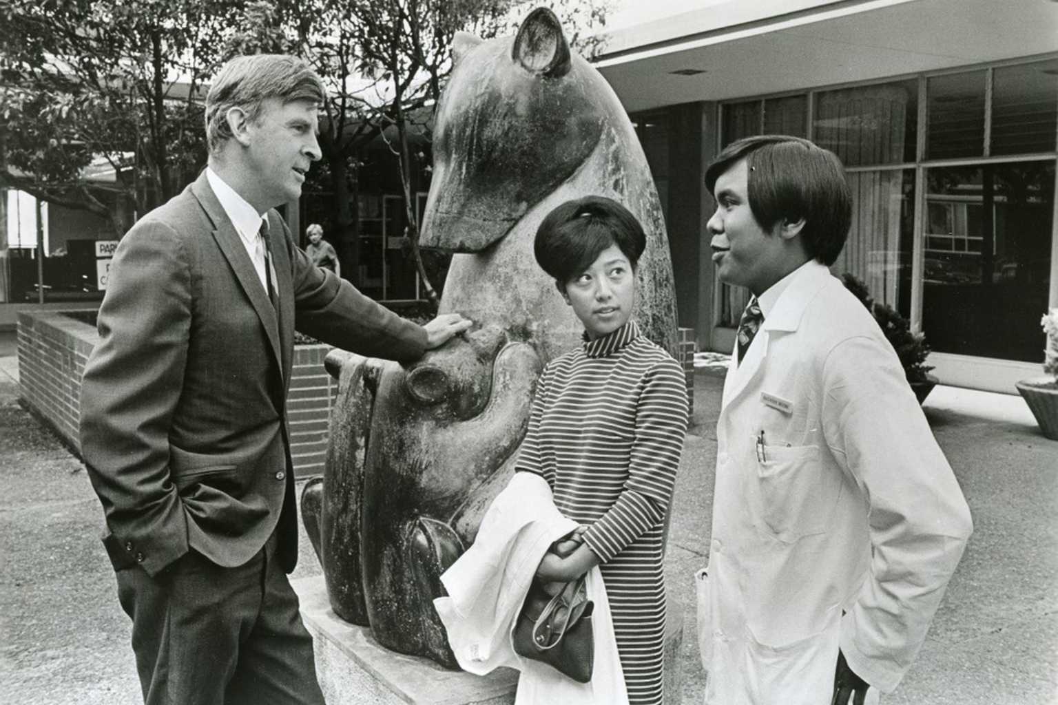  UCSF Chancellor Philip Lee with students in white lab coats in front of Beniamino Bufano’s Bear and Cubs sculpture.