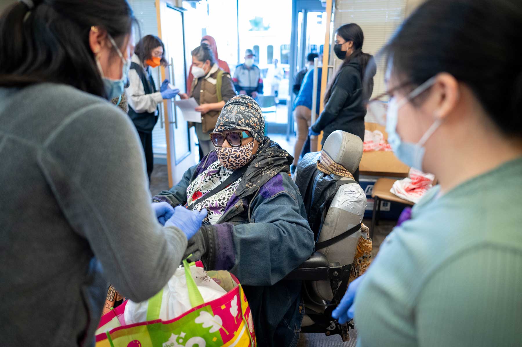 A woman in a wheelchair receives a bag full of food.