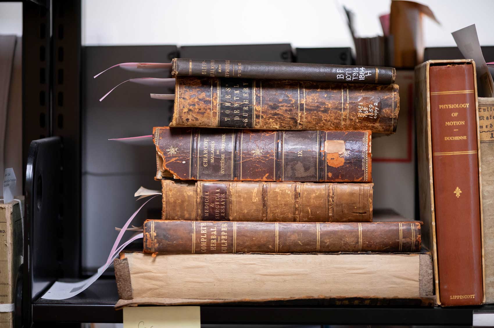 A stack of five old and thick leather-bound medical books sit on a shelf at the UCSF archives.