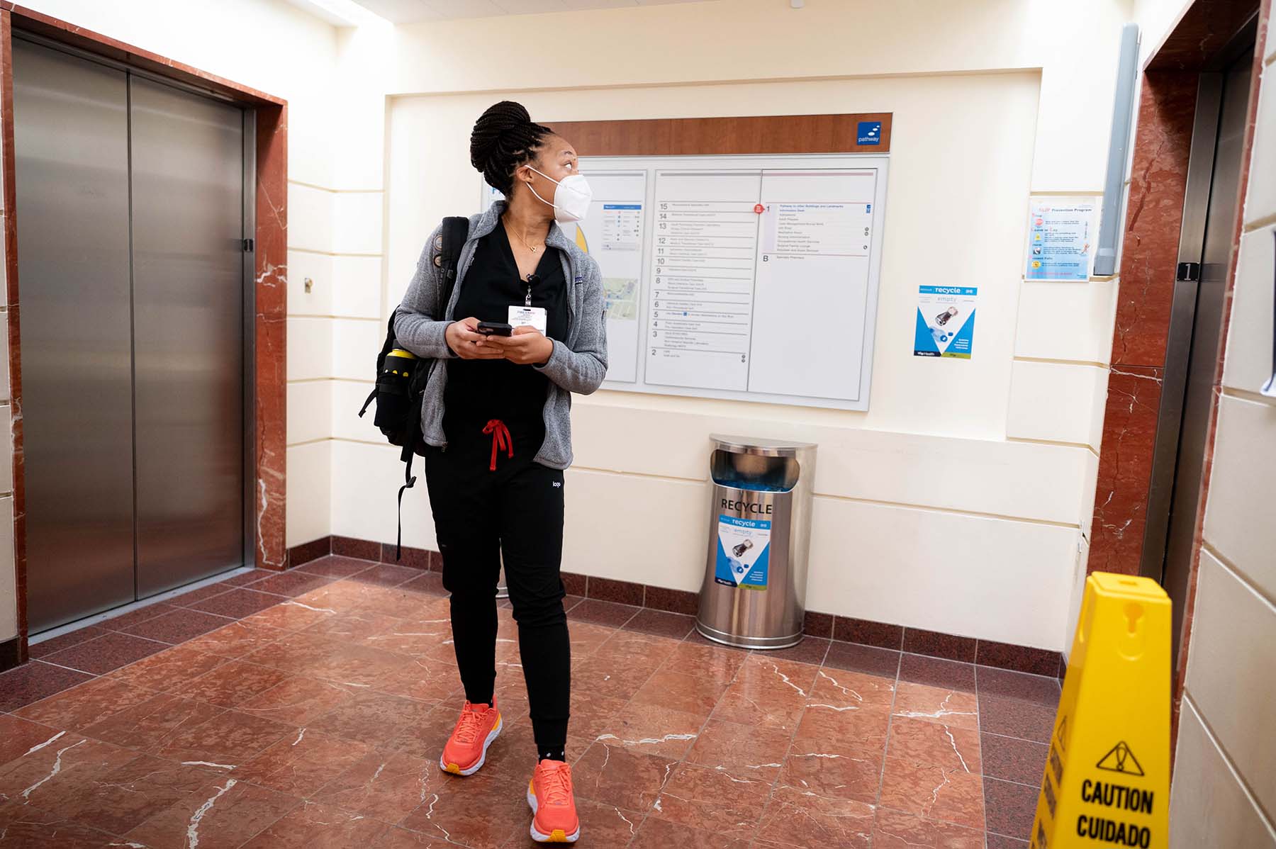 Kelechi Okpara holds her phone in her hand while she waits for an elevator at the UCSF Parnassus Heights campus.