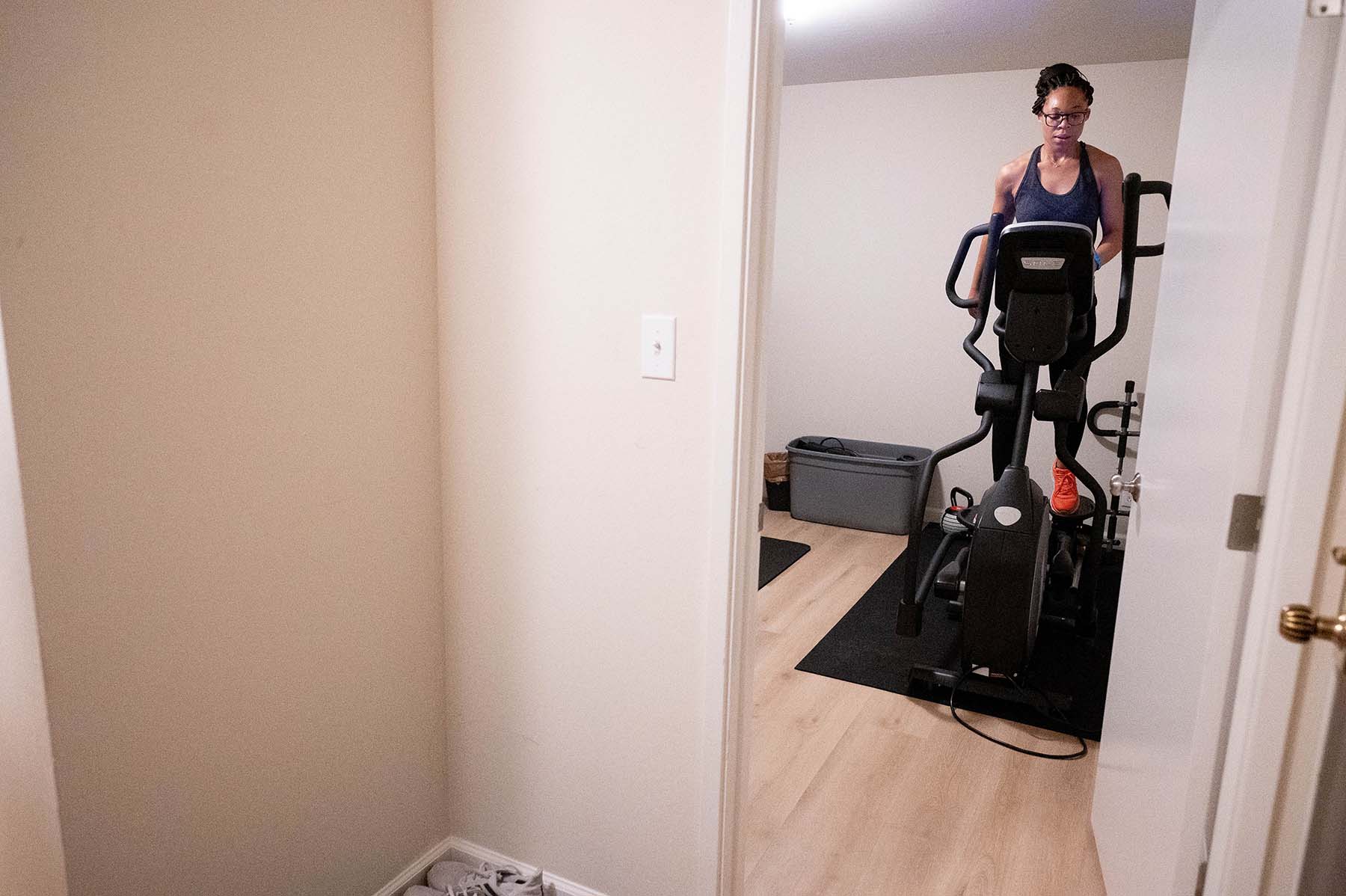 A young black woman named Kelechi Okpara exercises on an eliptical machine in her apartment early in the morning.