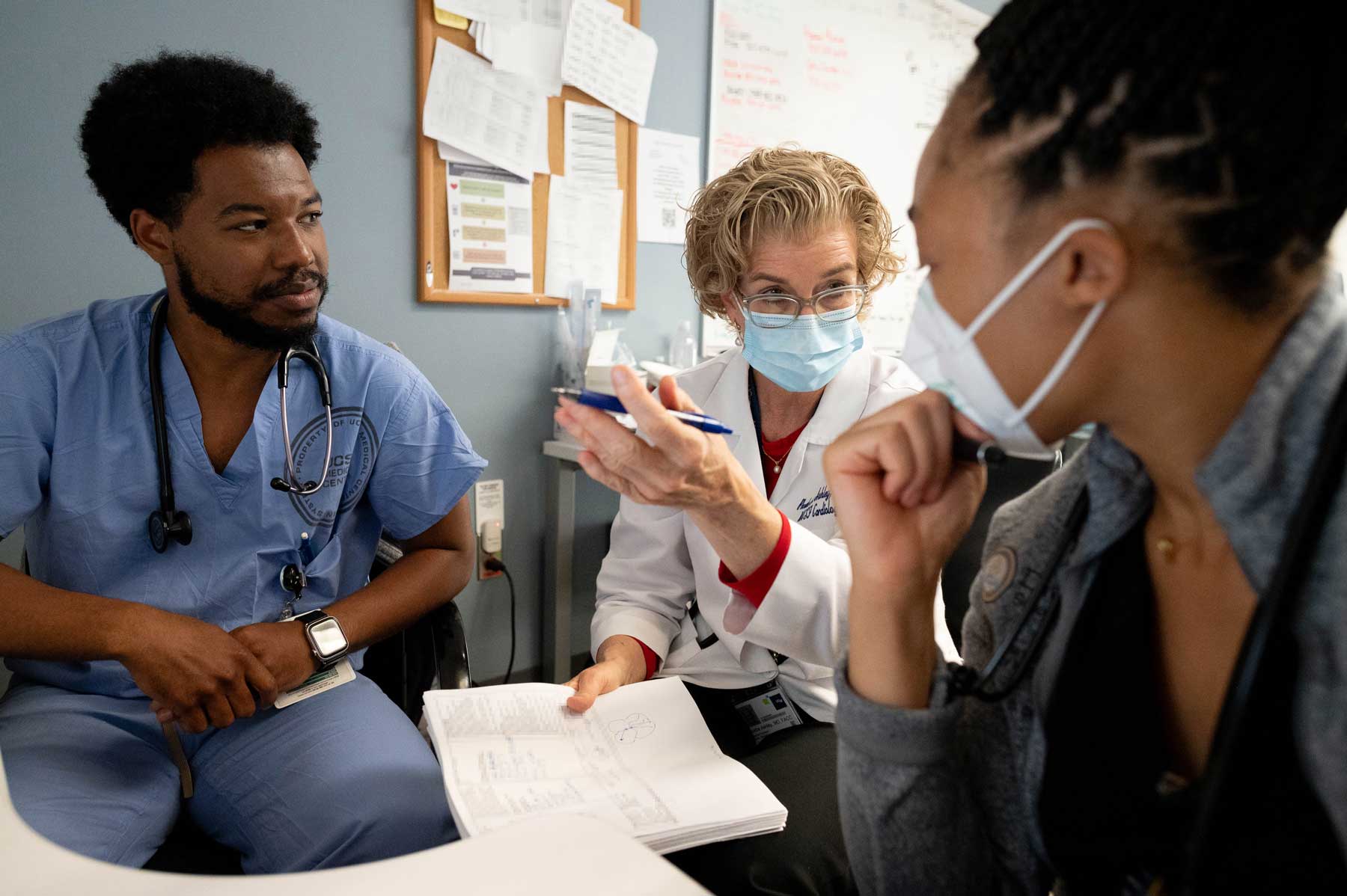 Senior resident Chris (left) and first-year resident (Kelechi) discuss a patient with a doctor (center).