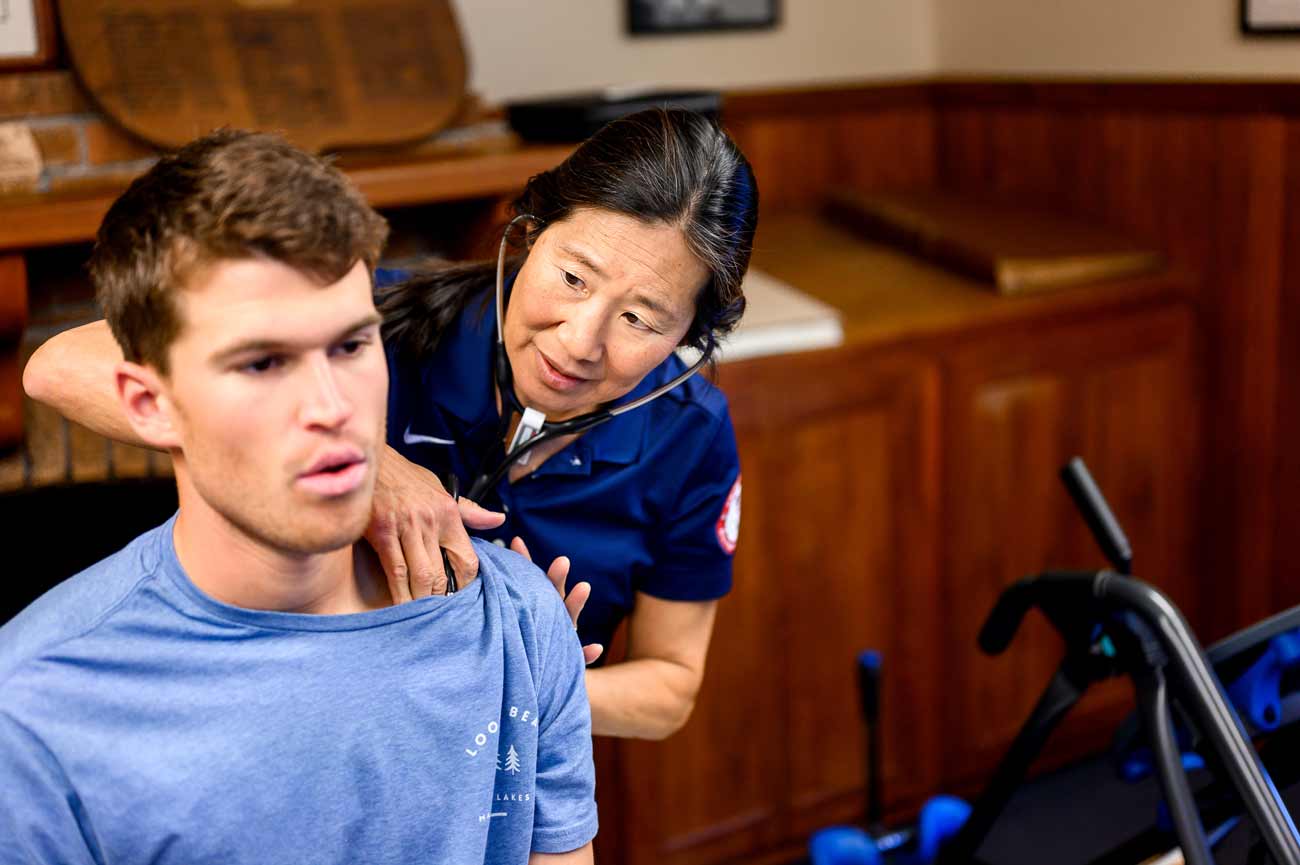 Cindy Chang wears a stethoscope as she listens to the breathing sounds of Kane Hall, a rower.