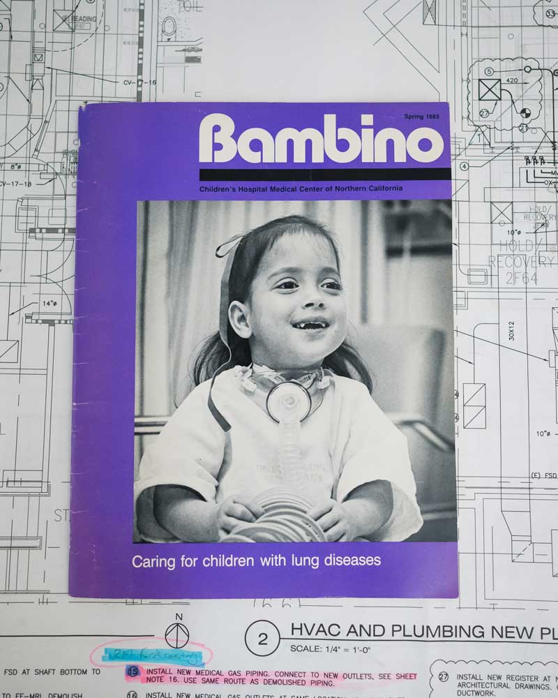 A copy of Bambino magazine, featuring three-year-old Michael Valero on the cover. It is placed on top of blueprints for the new MRI facility under construction at UCSF Benioff Children's Hospital Oakland.