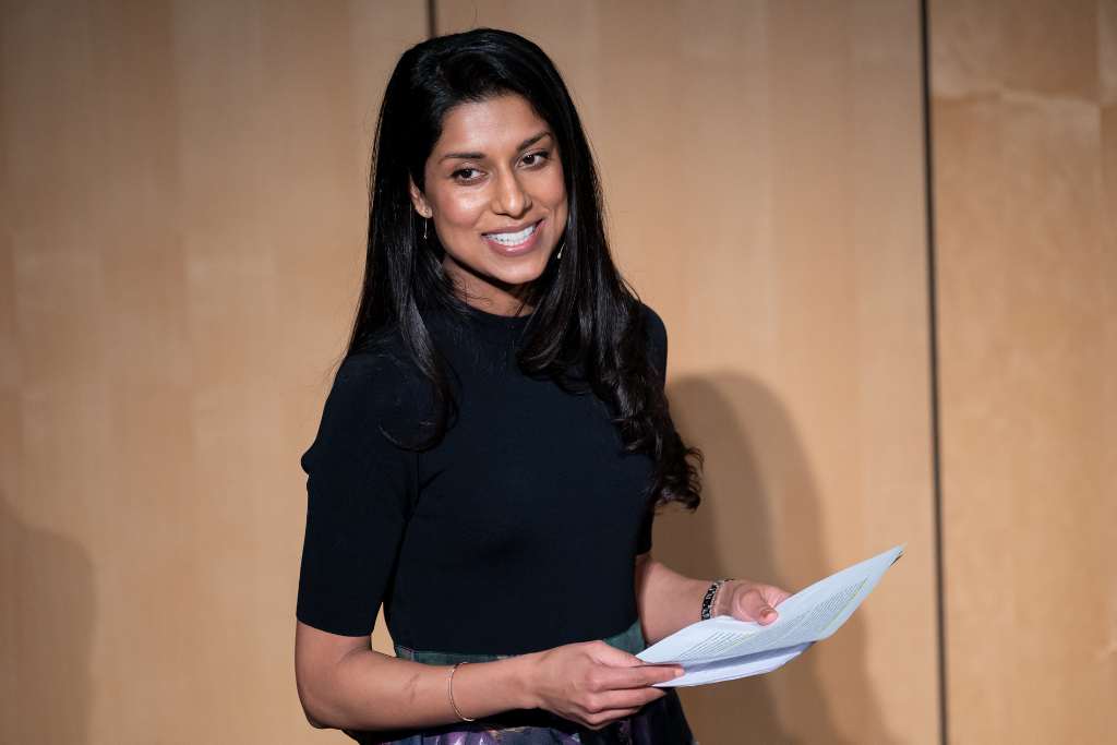 Rupa smiles at audience holding paper notes