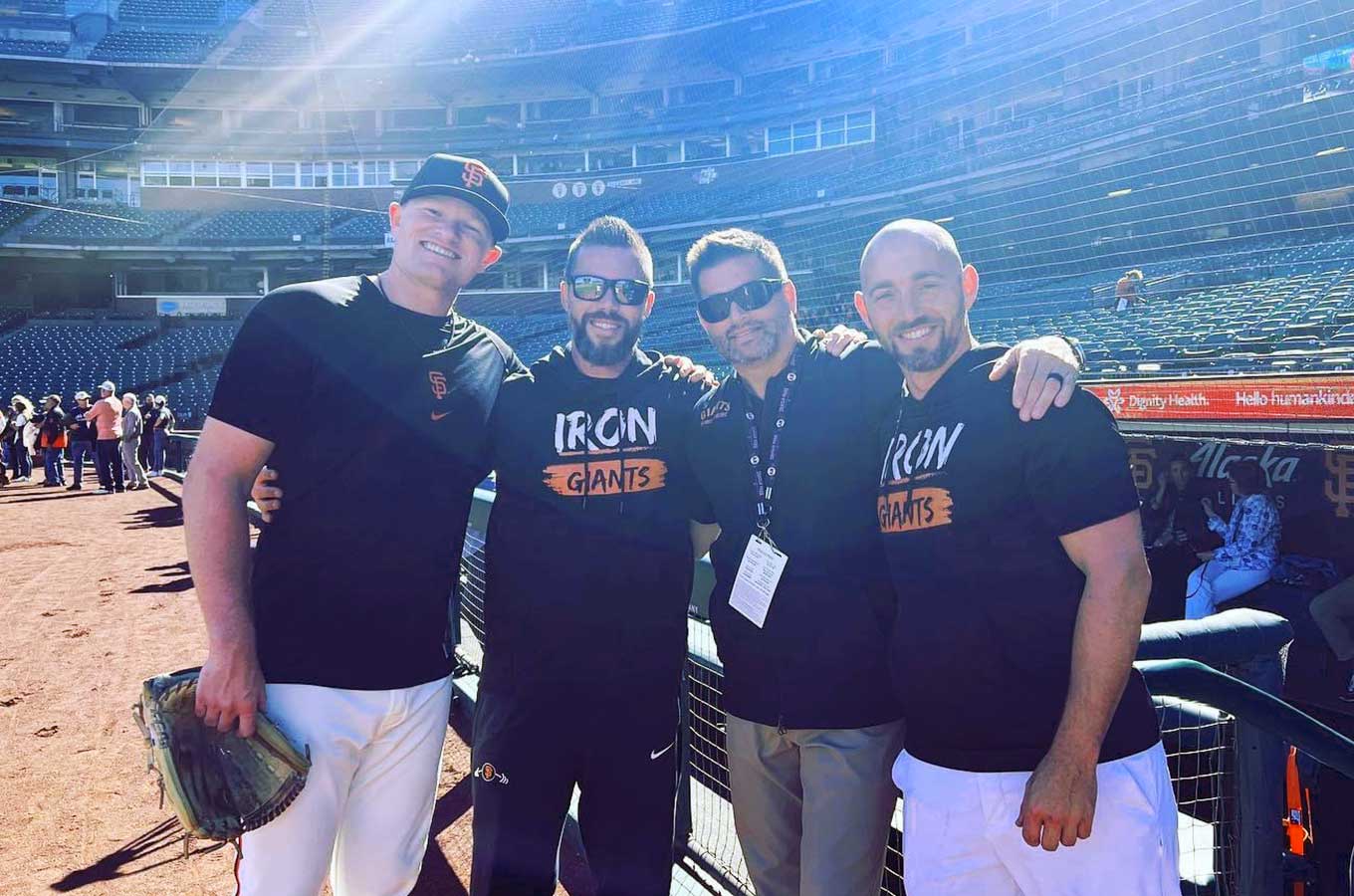 Surgeon Scott Hansen stands in a baseball field with Logan Webb and two men, who are part of the San Franscisco Giants' training staff.
