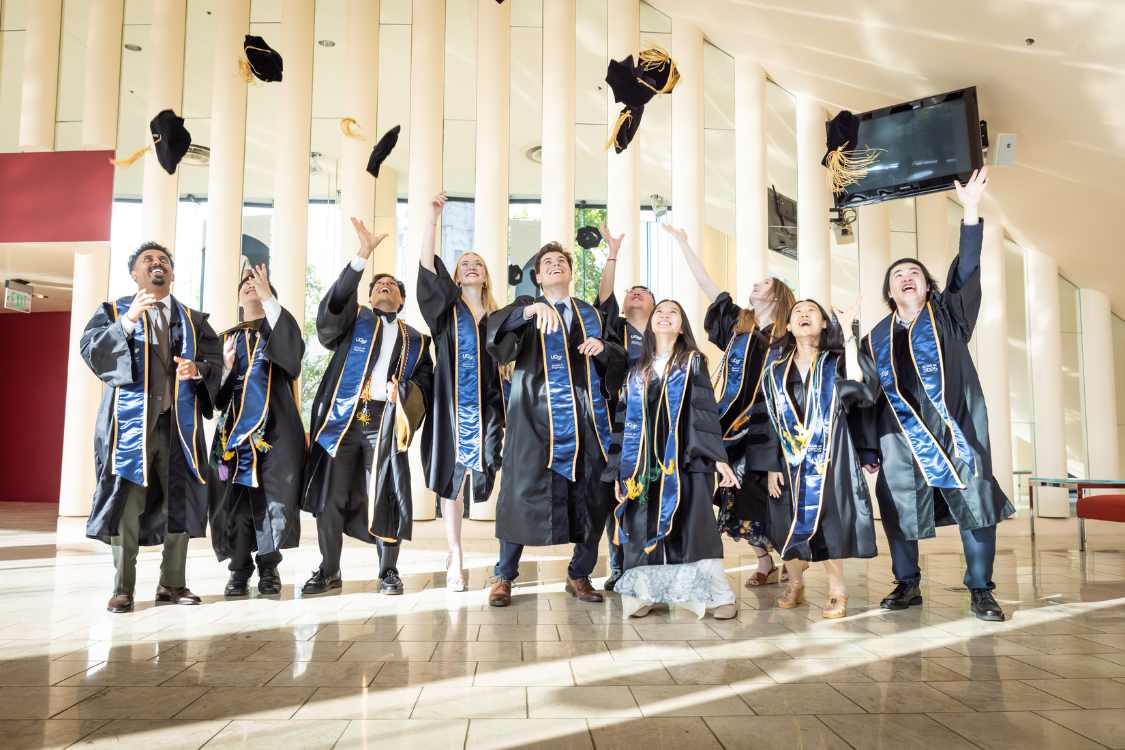 Group of graduates on a stage throwing their caps in the air