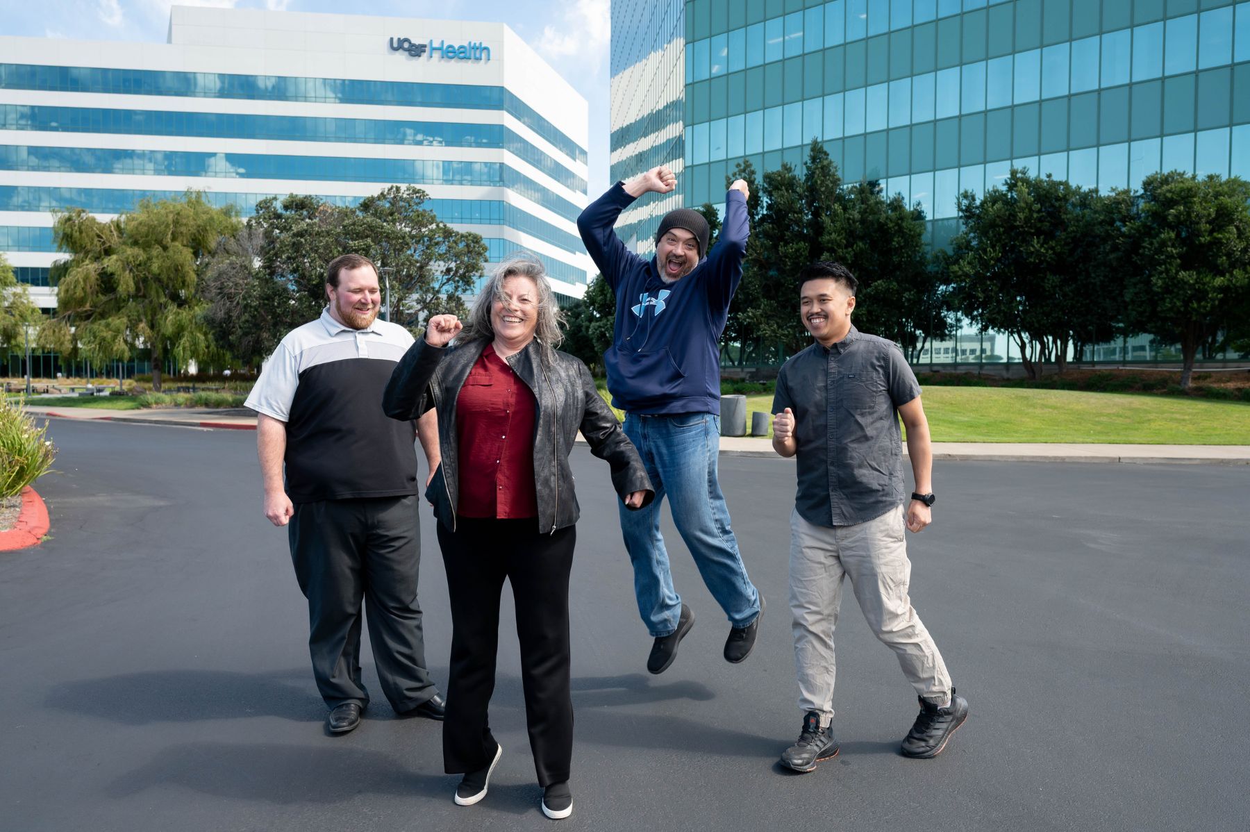 A group of four coworkers enthusiastically celebrating outdoors.