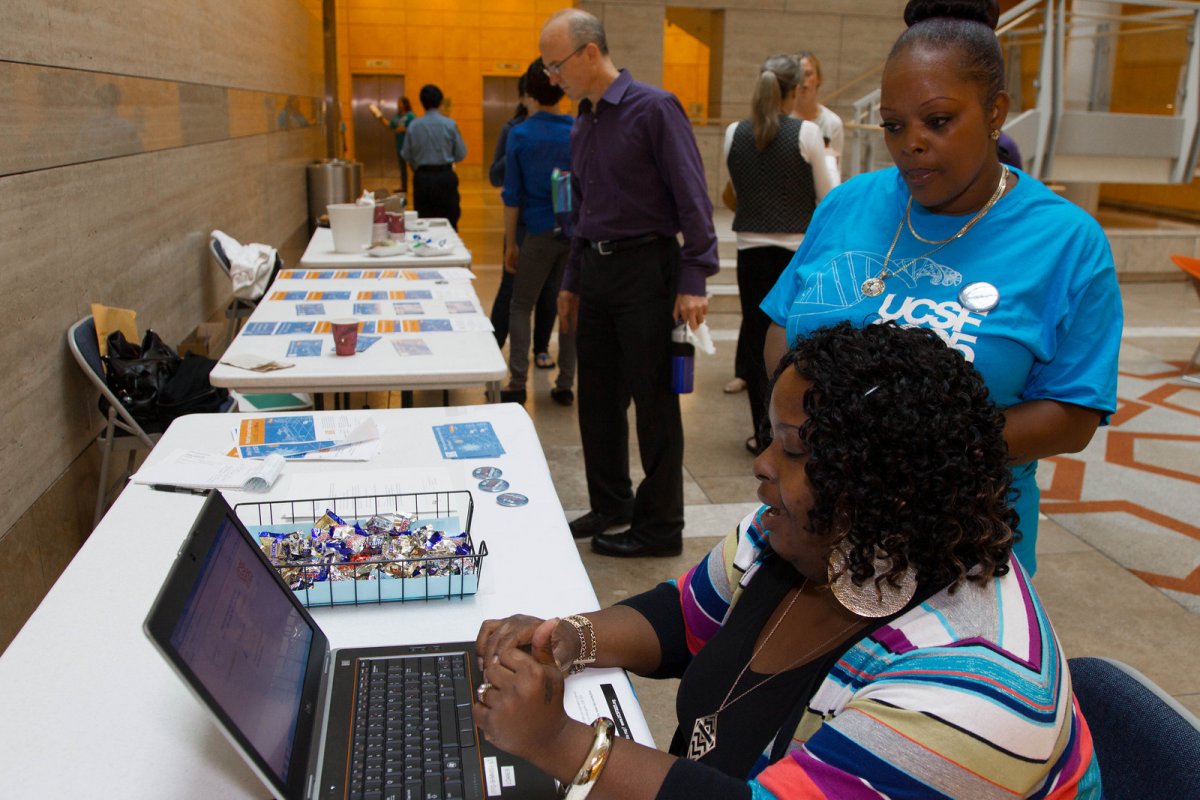 UCSF2025 volunteer Jackie White, an office manager in University Development and Alumni Relations, helps Sherrell Thompson sign up for the game at an informational booth.