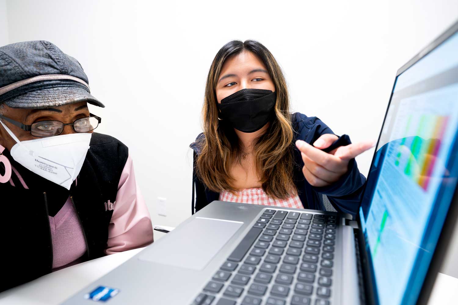 A clinical research coordinator shows data to a long COVID patient on a laptop screen.
