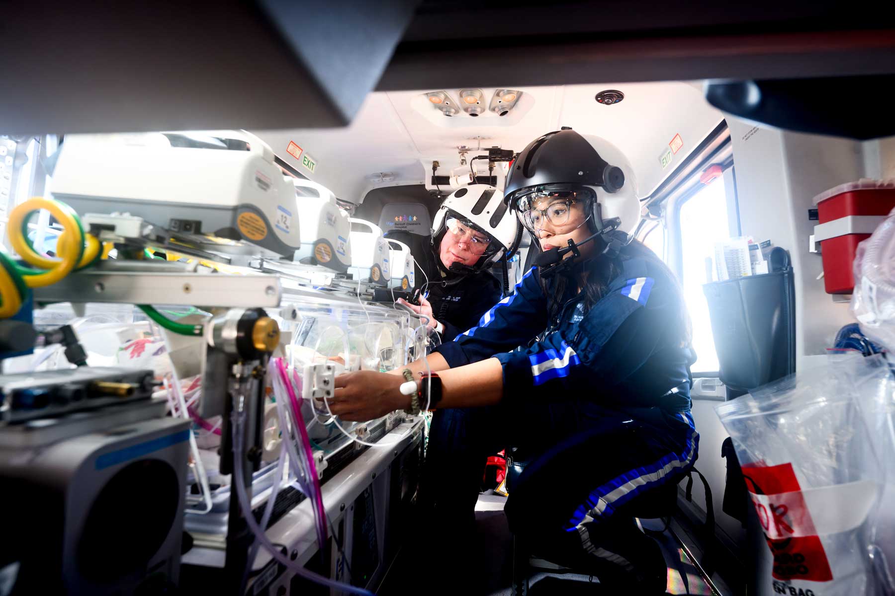 Two flight nurses wearing air craft helmets aboard a medical helicopter.