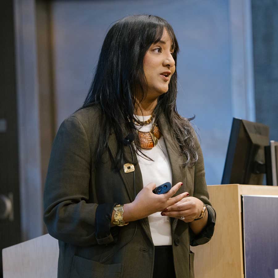 Rushika Perera stands onstage as she delivers a lecture.
