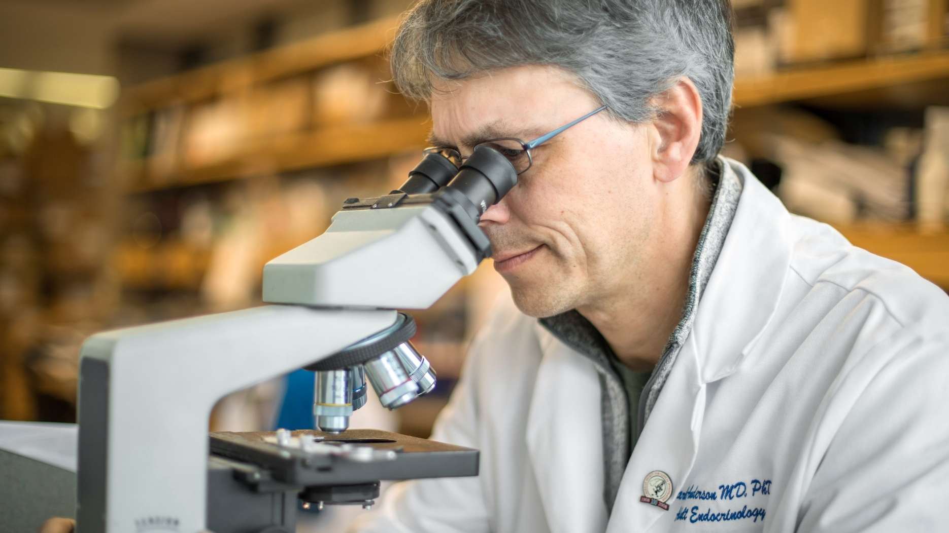 Professor Mark Anderson working with a microscope in a research laboratory setting.