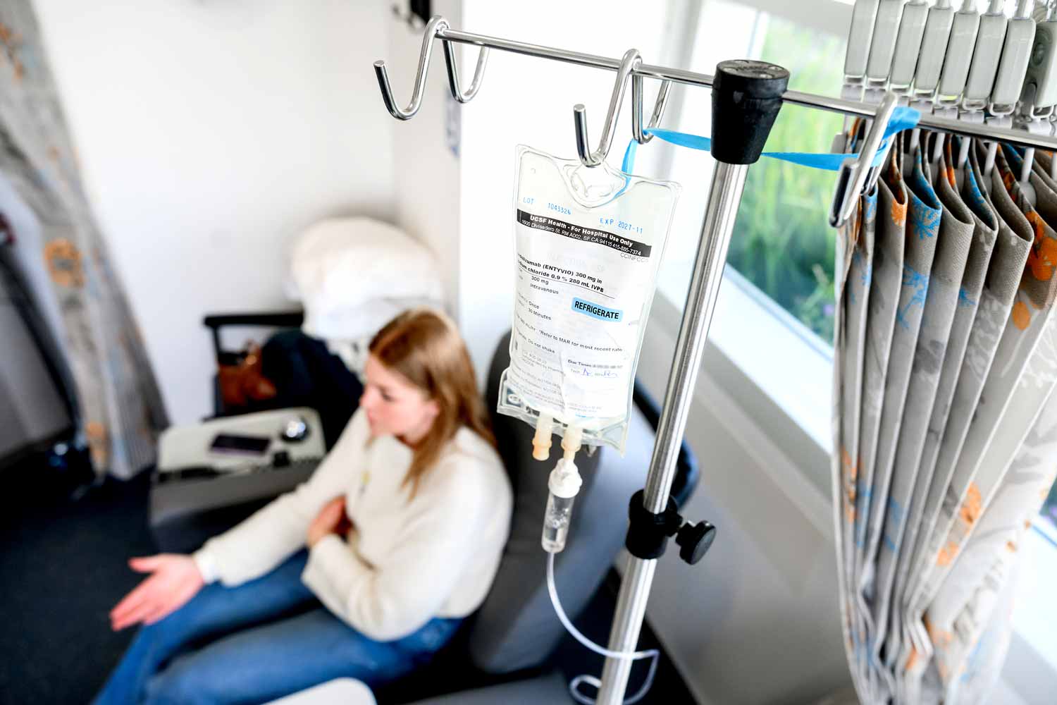 An infusion bag hangs from an IV pole as it is administered to a young female patient.