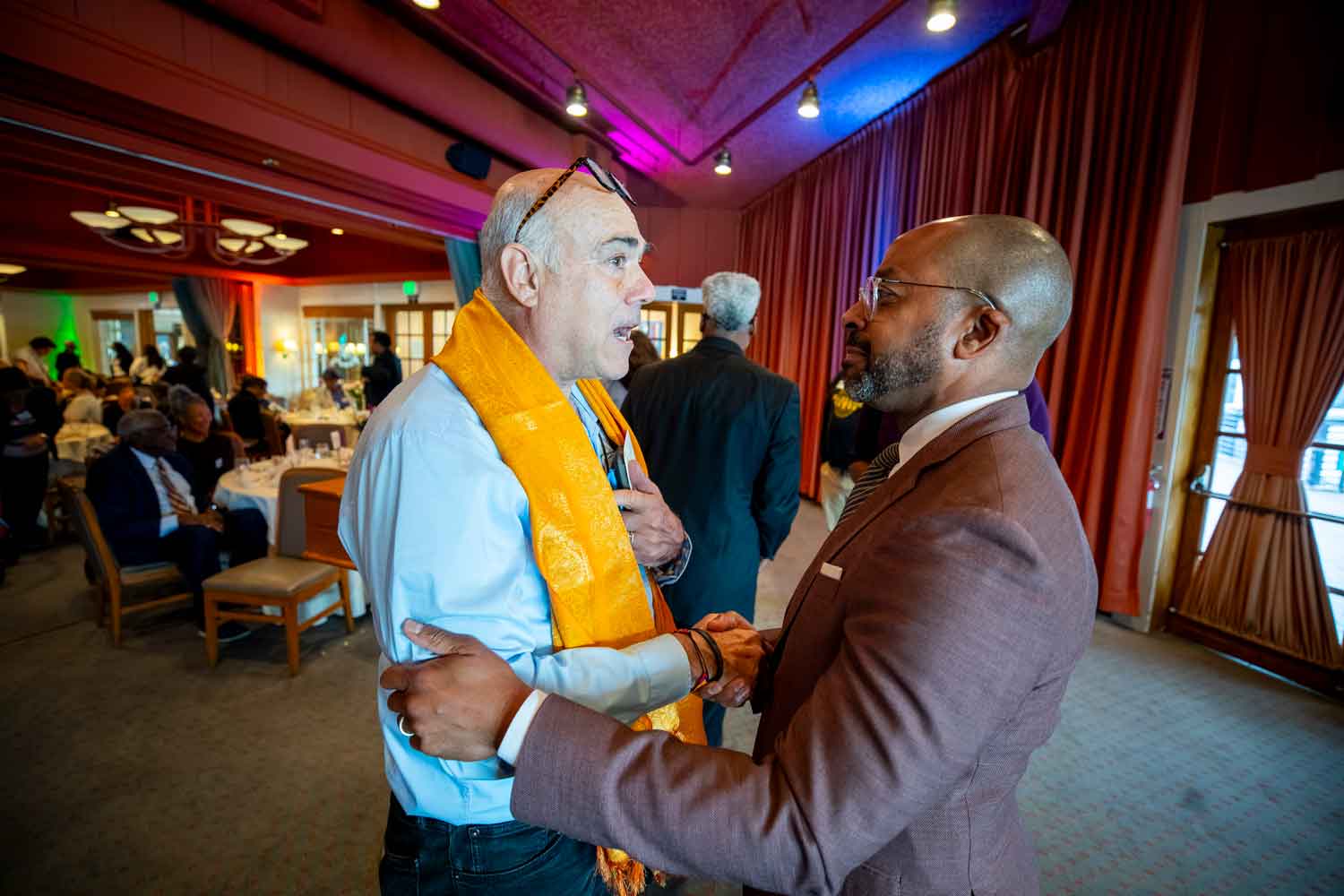 U C S F president Nichoals Holmes shakes hands with a community faith leader.