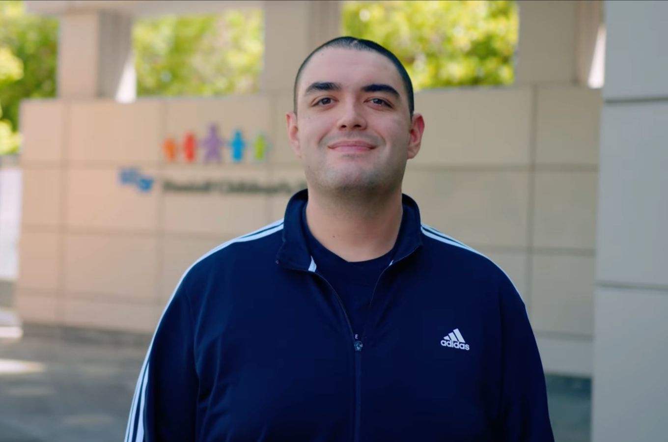 Andrew Santos smiles as she stands in front of U C S F Benioff Children's Hospital, San Francisco.