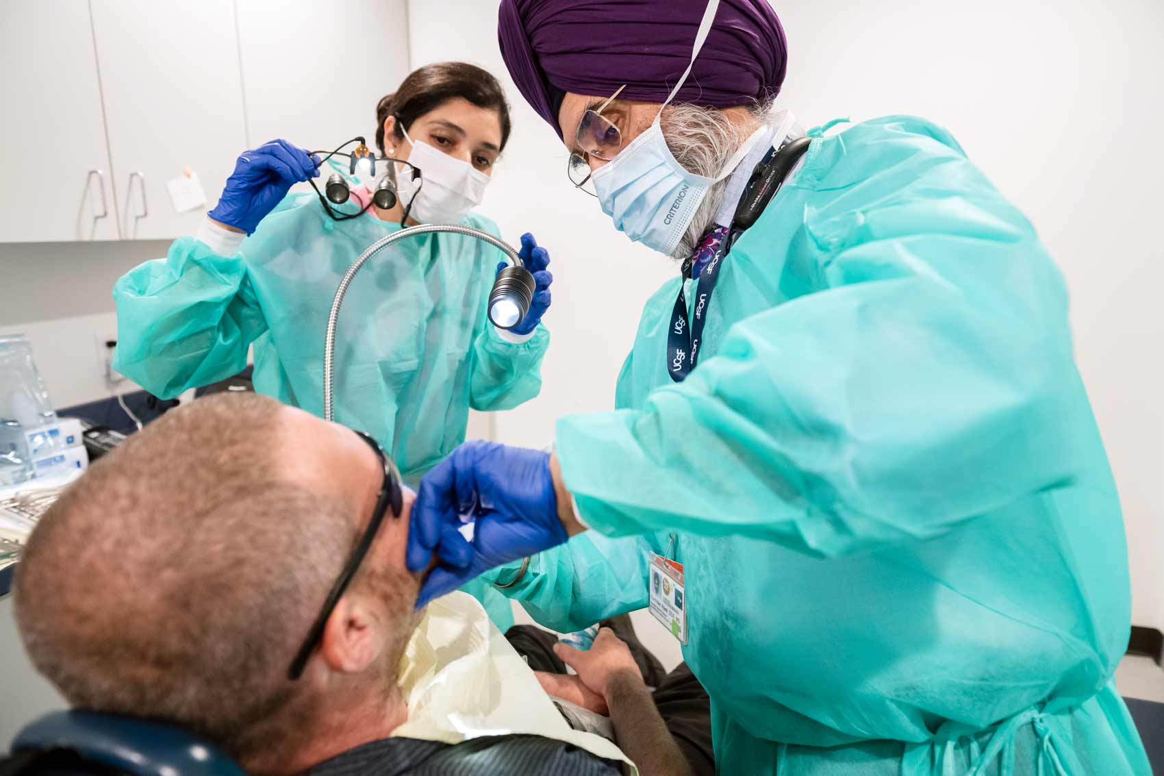 Two dental workers treat a patient.
