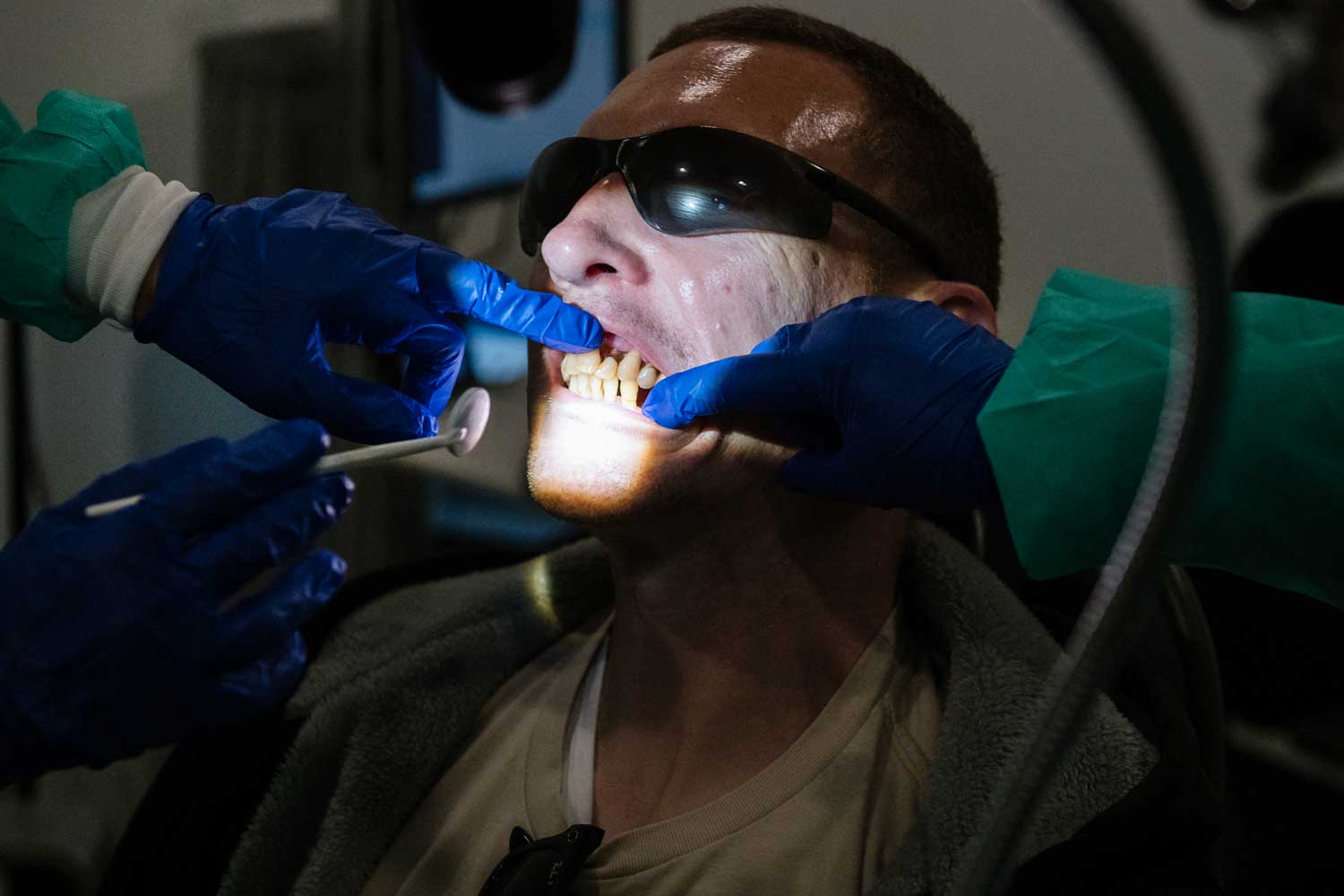 A closeup of two dentists examining decay in a man's tooth.